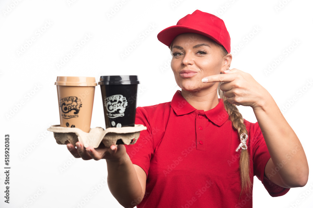 Woman in red uniform pointing on cups with coffee on white background Woman in red uniform pointing on cups with coffee on white background