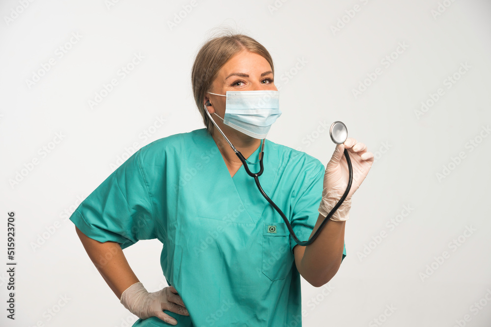Blonde female doctor wearing face mask and checking with stethoscope Blonde female doctor wearing face mask and checking with stethoscope