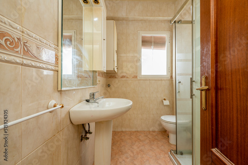 Bathroom with white wood-framed mirror  glass-enclosed shower stall  and white porcelain toilets