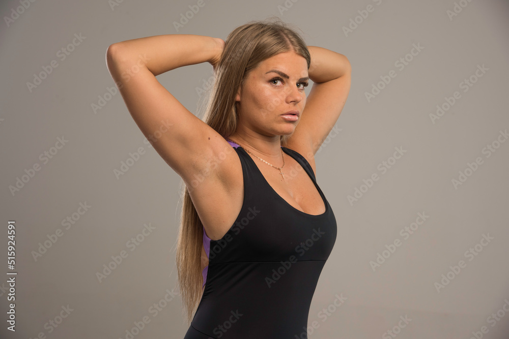 Fototapeta premium Female model in sport bra puts hands behind head