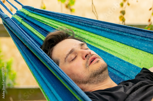 Tired father tries to sleep in hammock in garden