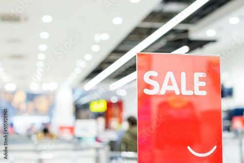 Discount percentage sign display in fashion department store during sale season period. Sale tag of offering special promotion hanging in shopping mall, Blurred department store background.
