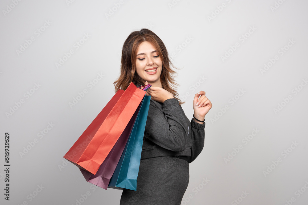 Photo of young woman with shopping bags and waving hand Photo of young woman with shopping bags and waving hand
