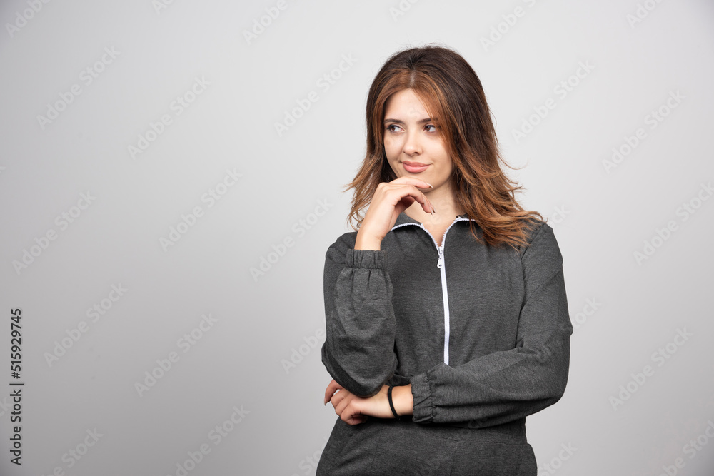 Young woman standing and looking away over a gray wall Young woman standing and looking away over a gray wall