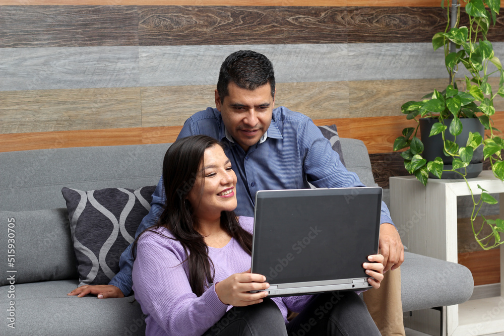 Latino adult man and woman couple use their laptop in the living room to shop online, make payments, plan trips, view photos and make video calls
Latino adult man and woman couple use their laptop in the living room to shop online, make payments, plan trips, view photos and make video calls