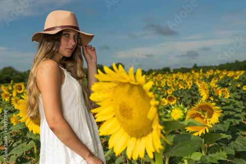 A Lovely Blonde Model Poses Outdoor While Enjoying The Summer Weather In A Field Of Wild Sunflowers