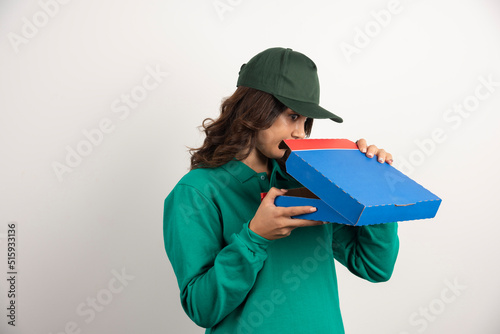 Hungry delivery woman opening pizza box on white background