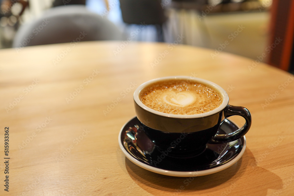 Coffee in black cup on wooden table in cafe with lighting background Coffee in black cup on wooden table in cafe with lighting background