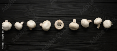 Fresh white mushrooms champignon on wooden background. Top view. Copy space.