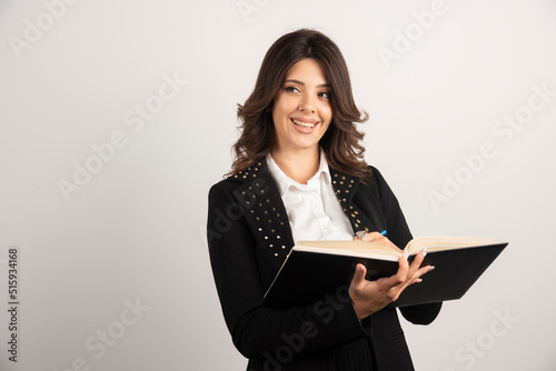 Positive teacher posing with open notebok photo