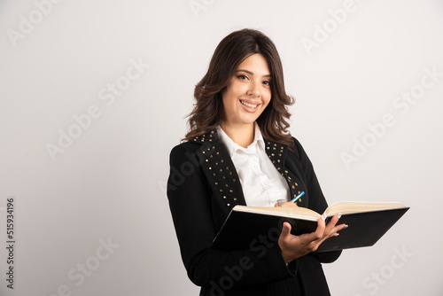 Positive teacher posing with open notebok photo