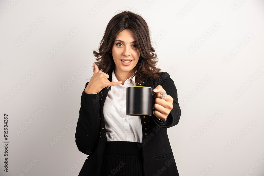 Female office worker offers a cup of tea and gesturing to call her Female office worker offers a cup of tea and gesturing to call her