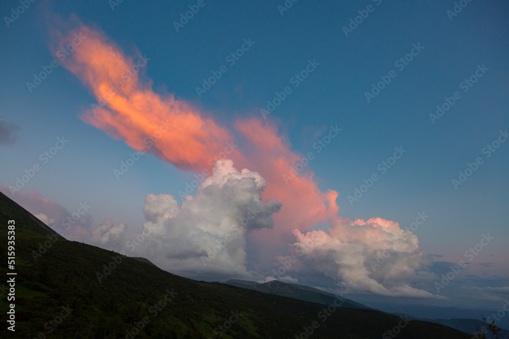 orange cirro-cumulus and cumulus clouds in the evening light at sunset in the mountains