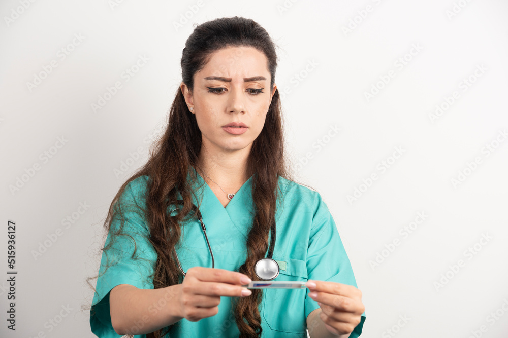 Female nurse with stethoscope looking on thermometer Female nurse with stethoscope looking on thermometer