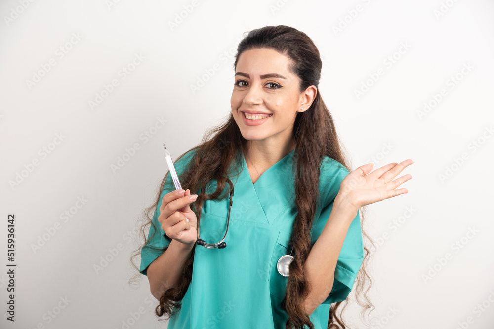 Portrait of smiling female healthcare worker posing with thermometer Portrait of smiling female healthcare worker posing with thermometer