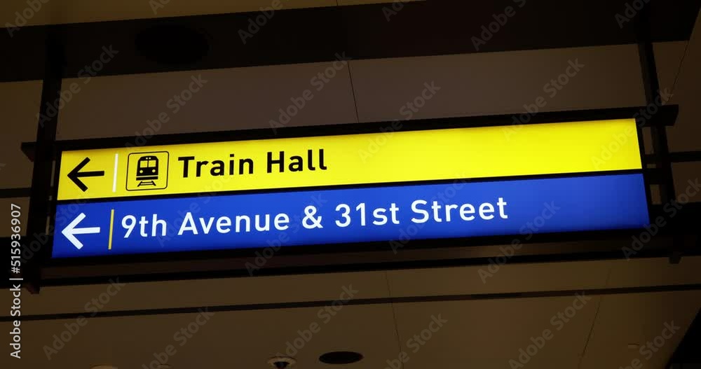 Signs to Trains, Train Hall and 9th Avenue & 31st Street. Illuminated yellow and blue Signs to Trains, Train Hall and 9th Avenue & 31st Street. Illuminated yellow and blue