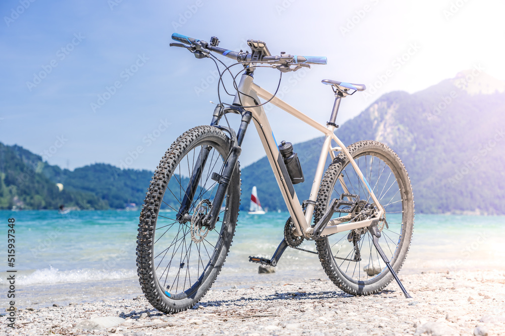 The bike stands against the backdrop of mountains and a lake