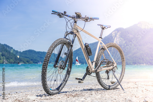 The bike stands against the backdrop of mountains and a lake © VINSI