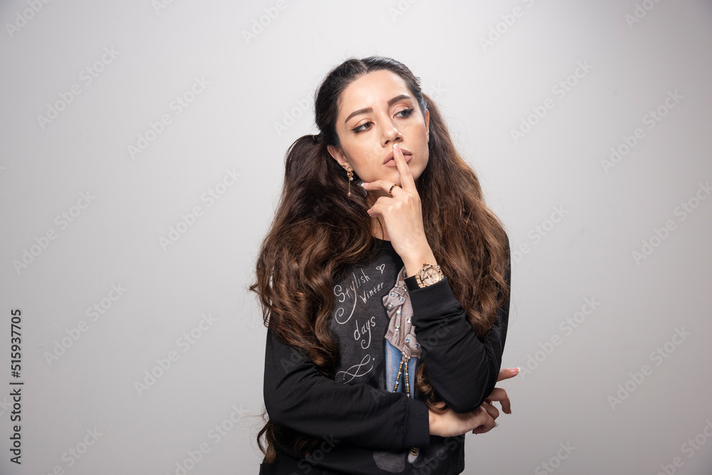 Young girl in printed sweatshirt thinking on gray background Young girl in printed sweatshirt thinking on gray background