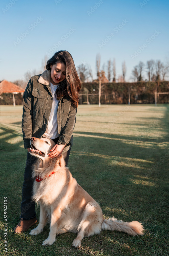 Obraz premium latin mature woman standing outdoors smiling with a retriever dog at sunset portrait