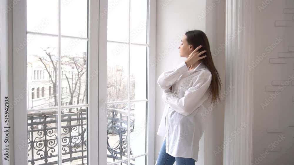 Beautiful young brunette Caucasian woman looks out the window Beautiful young brunette Caucasian woman looks out the window