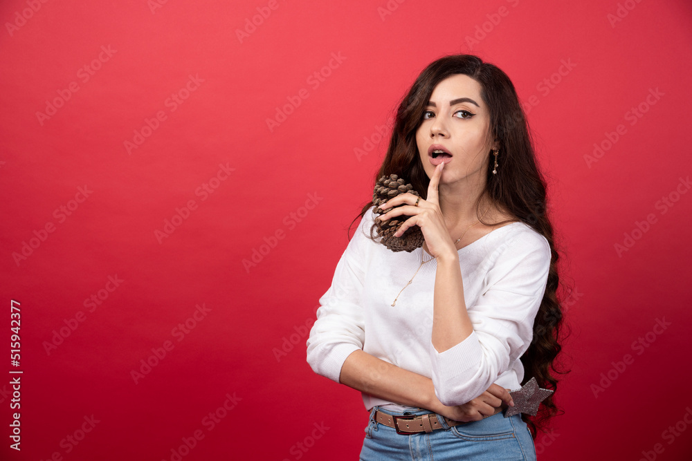 Elegant woman holding a big Christmas pinecone on red background