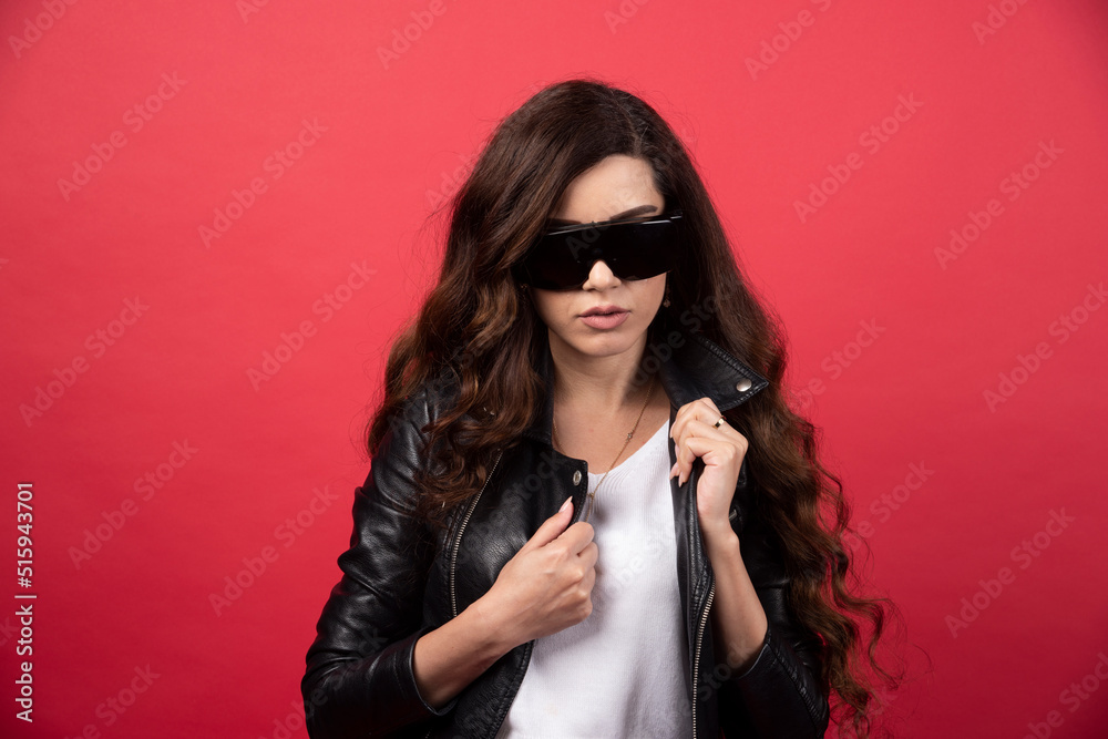Young woman posing with black glasses on a red background Young woman posing with black glasses on a red background