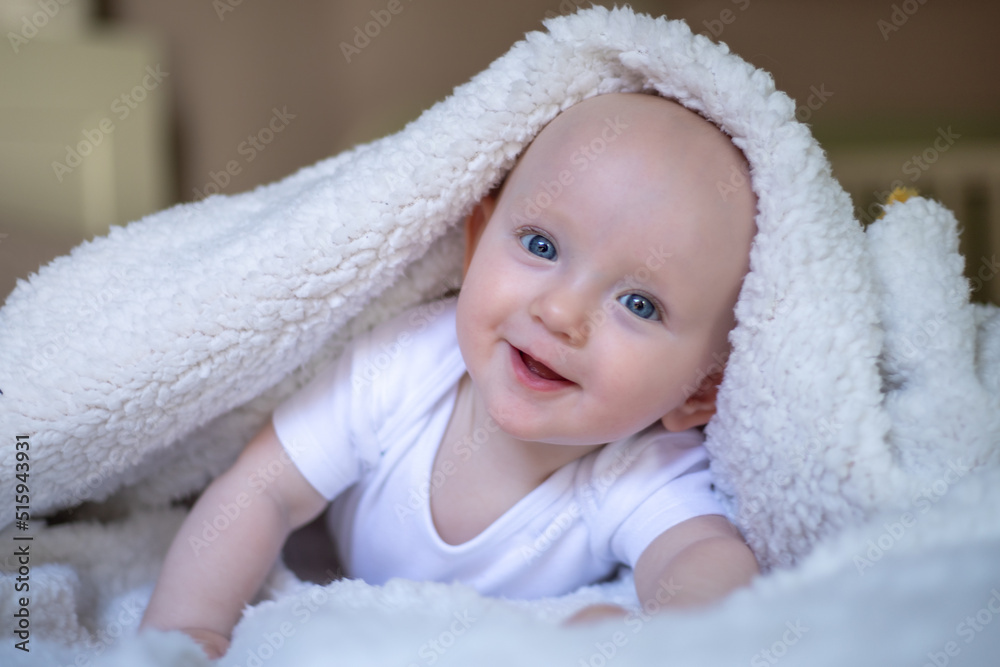 smiling baby looking at camera under a white blanket, towel. selective focus smiling baby looking at camera under a white blanket, towel. selective focus