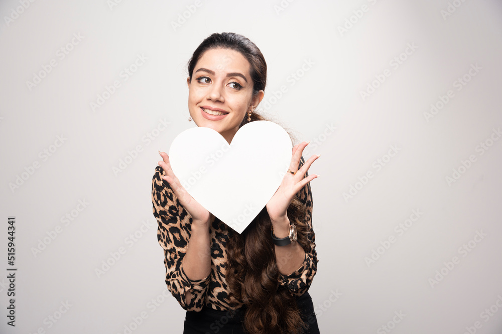 Businesswoman in leopard printed shirt holding a heart shape blank board Businesswoman in leopard printed shirt holding a heart shape blank board