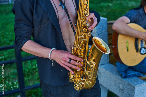 A street musician plays the saxophone. Duo saxophone and acoustic guitar. Street concert