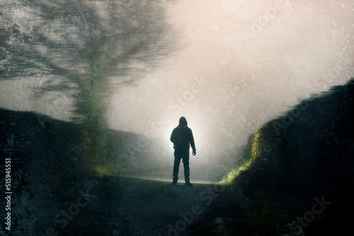 A man looking down a country road, silhouetted against torch light. On a spooky foggy winters night.