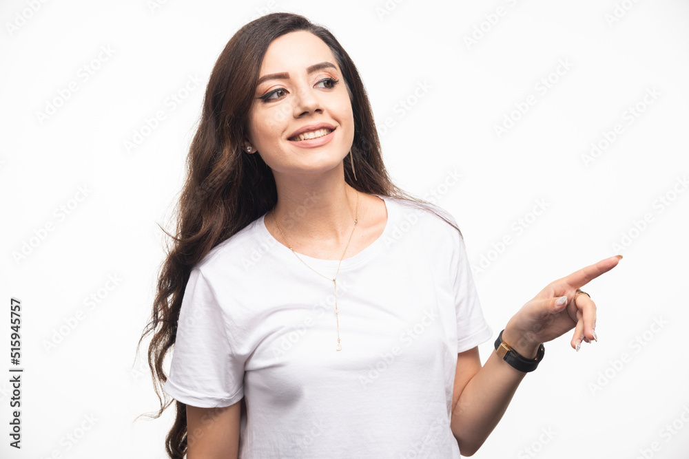 Fototapeta premium Attractive woman in white shirt pointing at somewhere