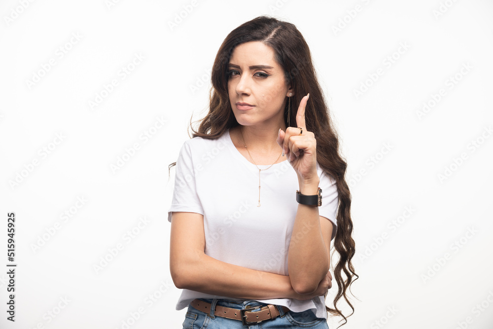 Long haired woman in white shirt pointing at up side Long haired woman in white shirt pointing at up side