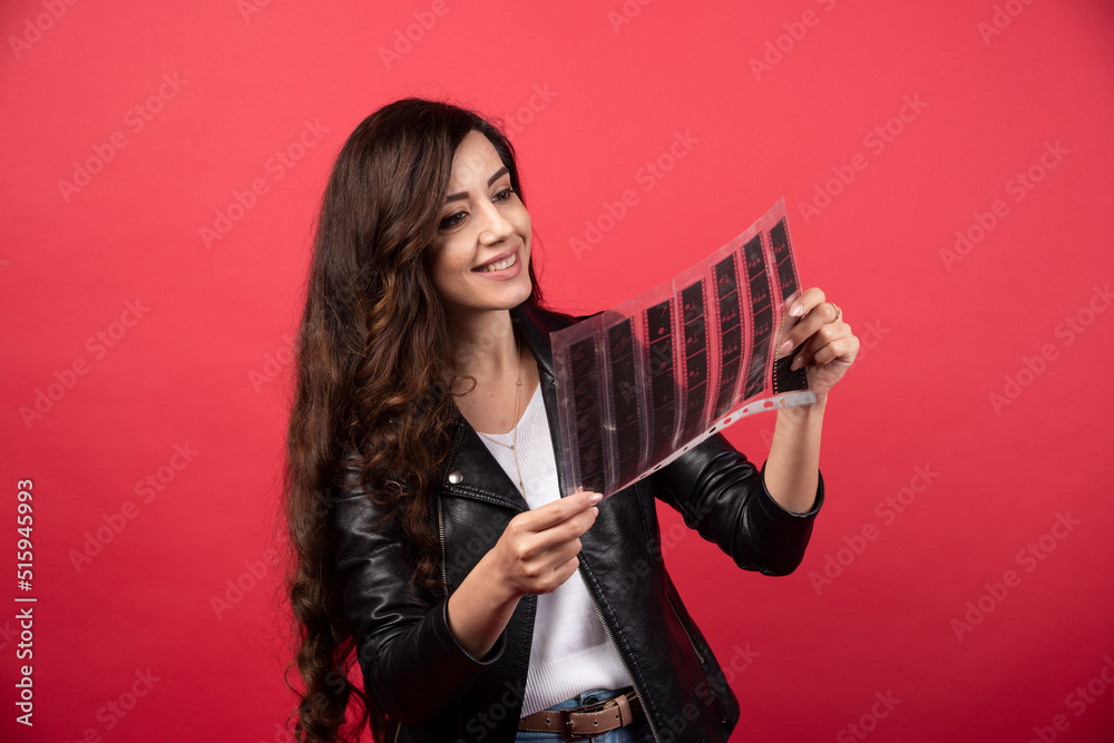 Young woman looking on a file with a photo tape on a red background