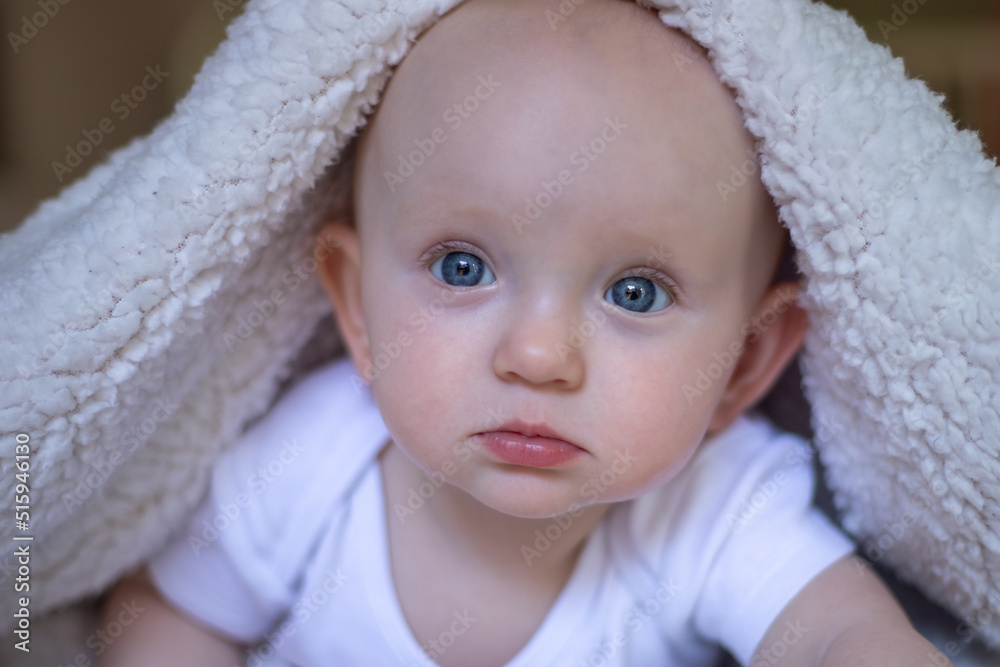 smiling baby looking at camera under a white blanket, towel. selective focus smiling baby looking at camera under a white blanket, towel. selective focus
