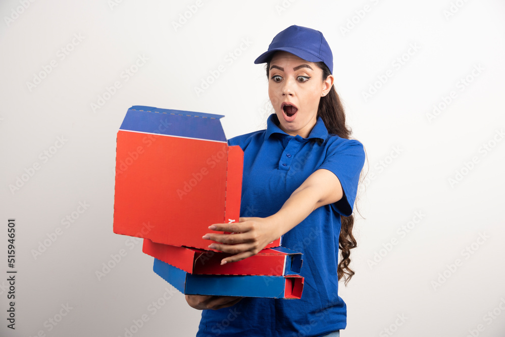 Wondering female courier with cardboard of pizza and clipboard Wondering female courier with cardboard of pizza and clipboard