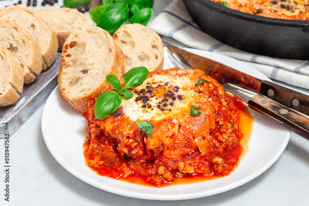 Shakshuka with eggs, Italian sausage, tomato sauce, on a white plate, horizontal Shakshuka with eggs, Italian sausage, tomato sauce, on a white plate, horizontal