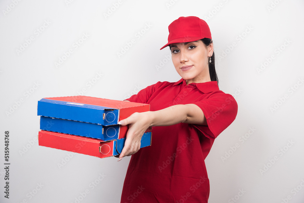 Young delivery woman with cap holding a three boxes of pizza on white background Young delivery woman with cap holding a three boxes of pizza on white background