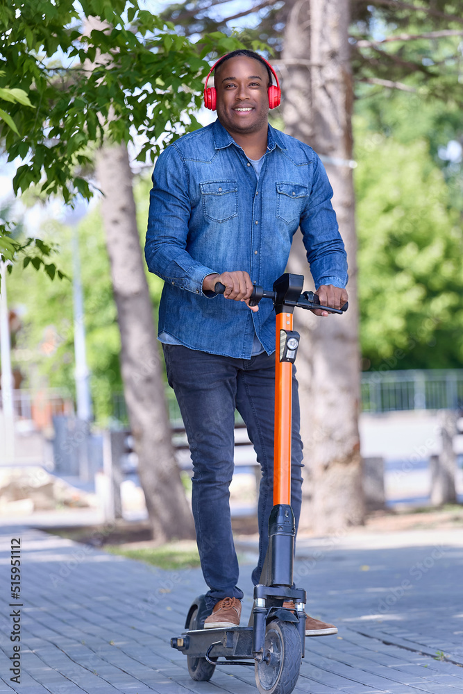 An African male freelancer works remotely, moves around the city on an electric scooter. Modern online work allows employees to be outside the office, to work in a convenient place