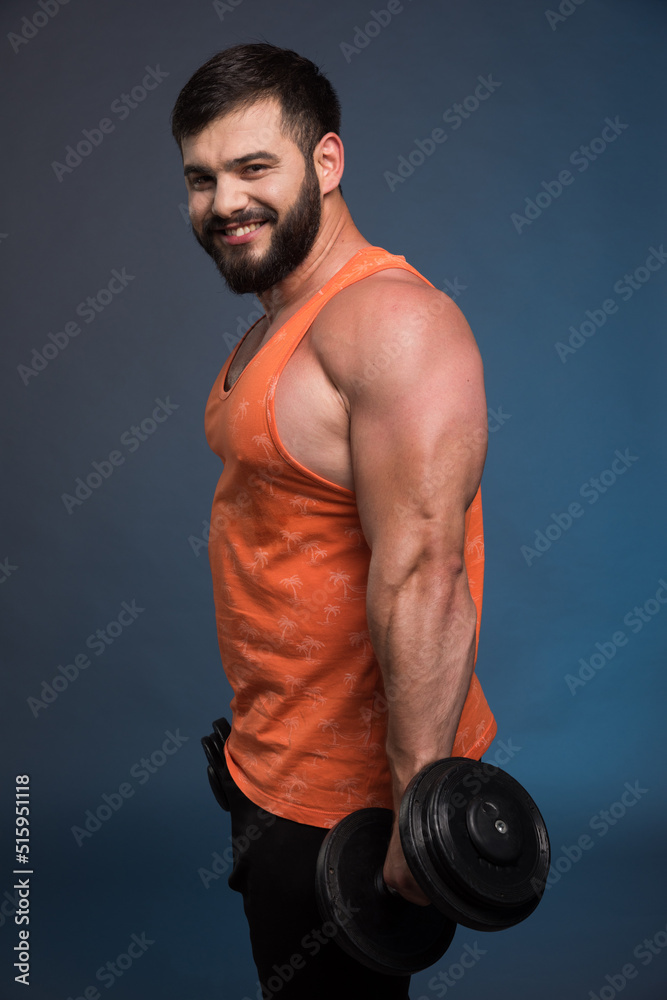 Strong man holding a dumbbell on dark blue background