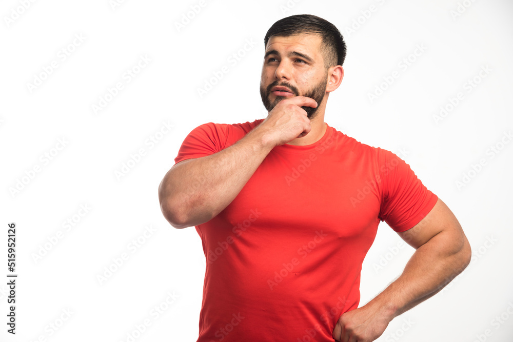 Sportive man in red shirt demonstrating his arm muscles and looks confident Sportive man in red shirt demonstrating his arm muscles and looks confident
