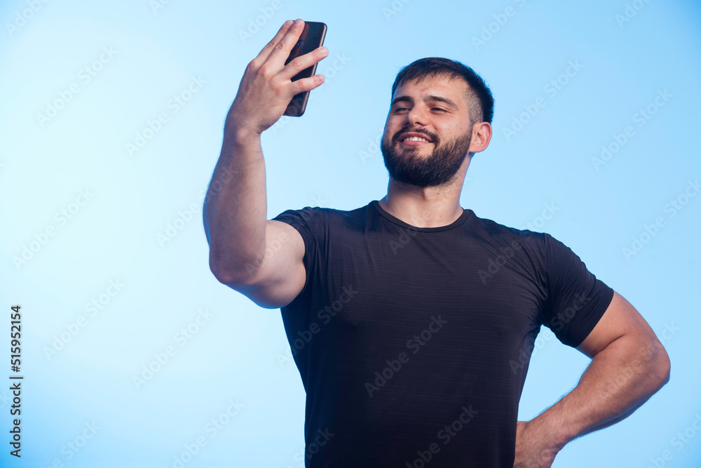 Sportive man in black shirt holds the phone and taking selfie Sportive man in black shirt holds the phone and taking selfie