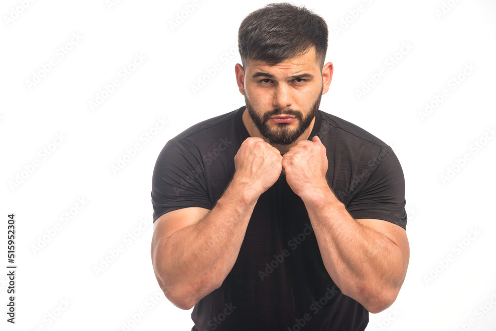 Sportive man in black shirt showing his fists Sportive man in black shirt showing his fists