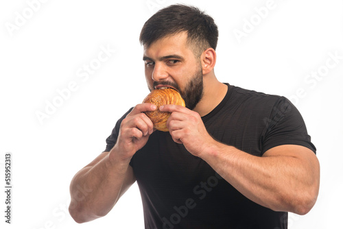Sportive man in black shirt eating a doughnut