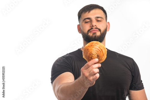 Sportive man in black shirt showing doughnut and his indifference