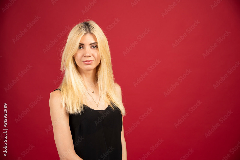 Fototapeta premium Portrait of blonde woman standing on red background