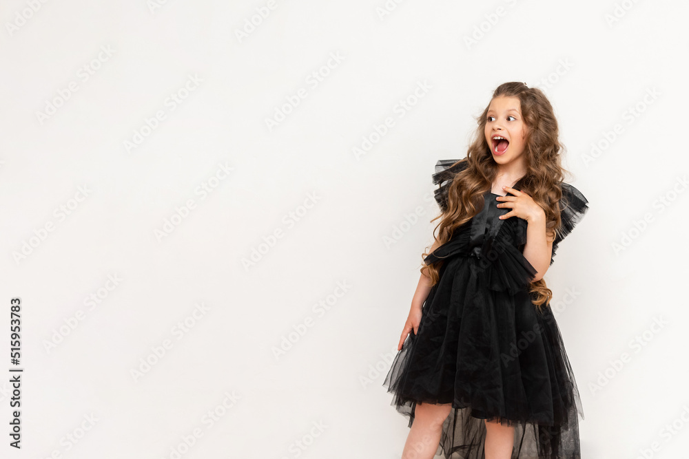 A beautiful child looks at your advertisement on a white isolated background. A charming little girl with curly hair and a fluffy dress. A beautiful child looks at your advertisement on a white isolated background. A charming little girl with curly hair and a fluffy dress.