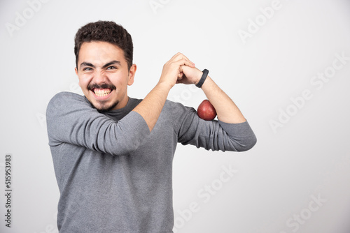 Brunette man posing with red apple on gray background
