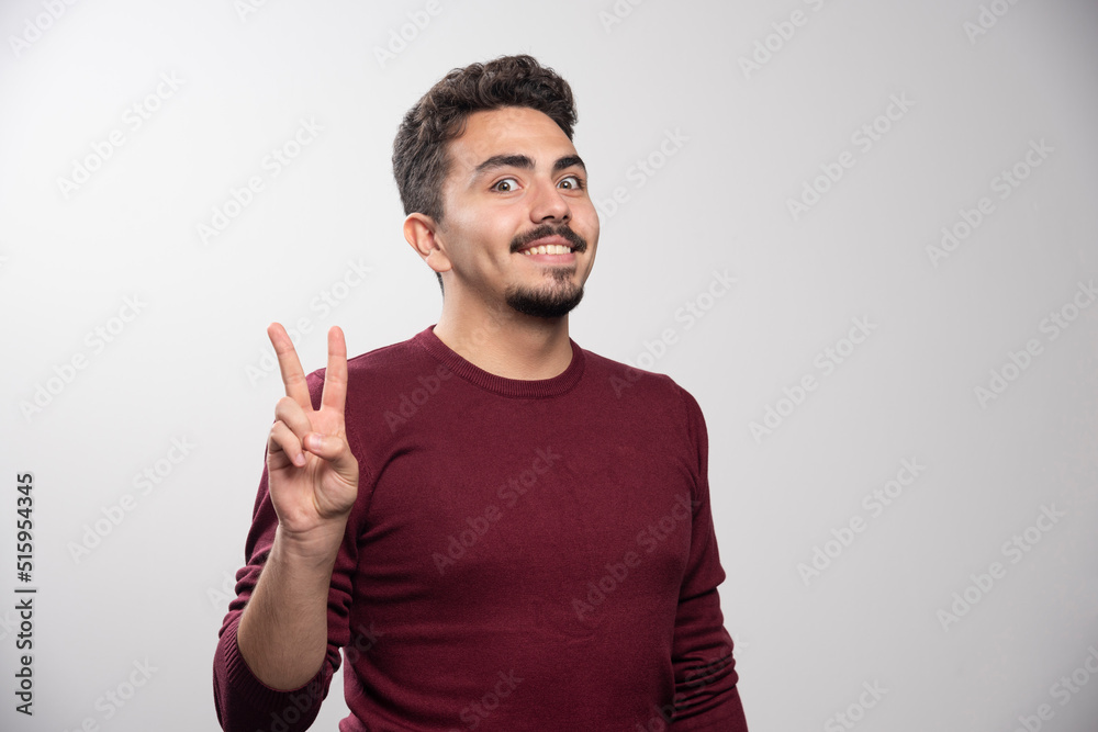 A smiling brunette man showing a victory sign A smiling brunette man showing a victory sign
