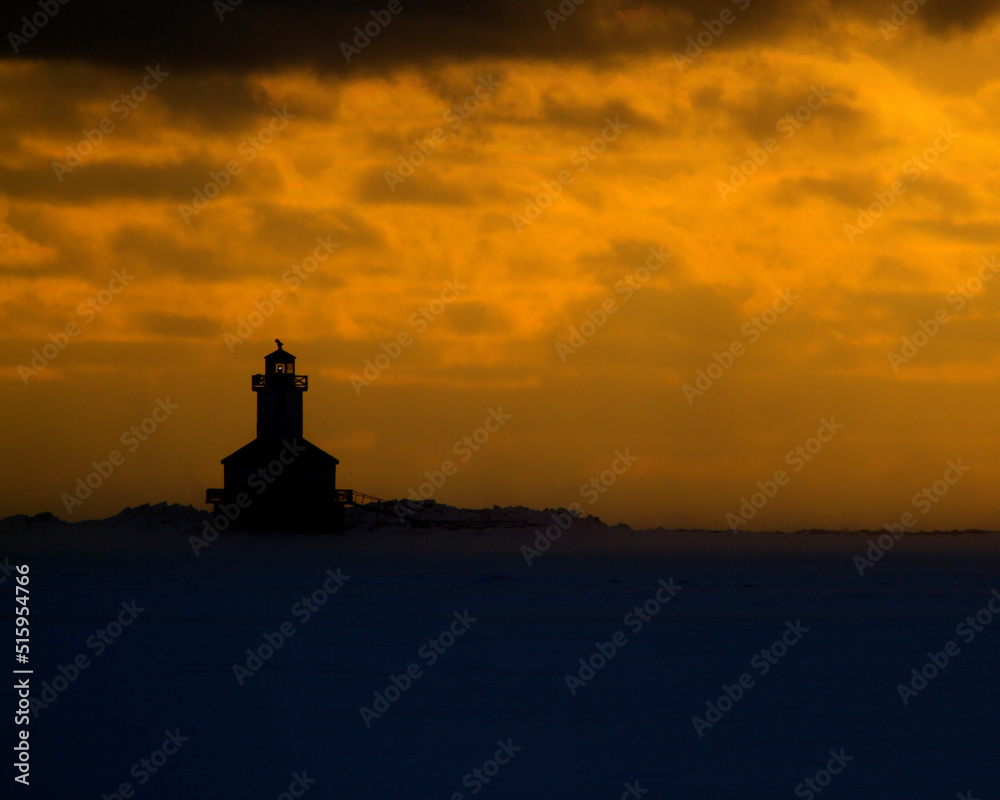 lighthouse at sunset on frozen coast